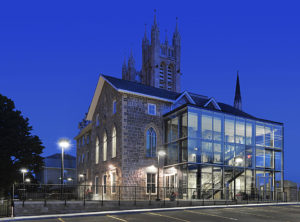 Exterior image of Guelph Civic Museum at night with the Church of Our Lady in the background.