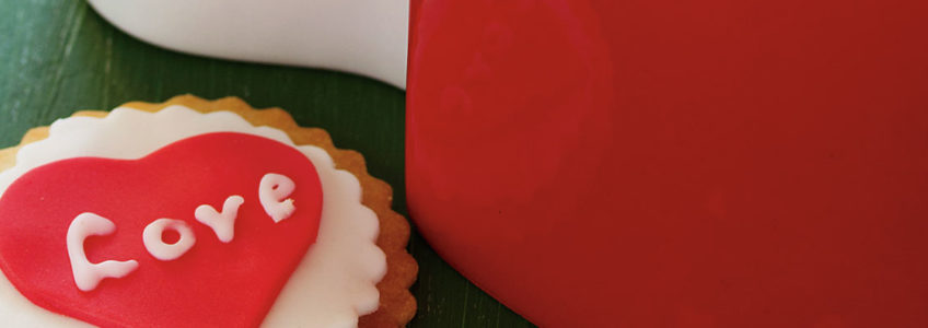 A sugar cookie decorated with a red head sits next to a red mug.