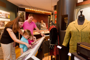 Photo of a family with two young kids looking at an exhibit panel in the City Gallery. 