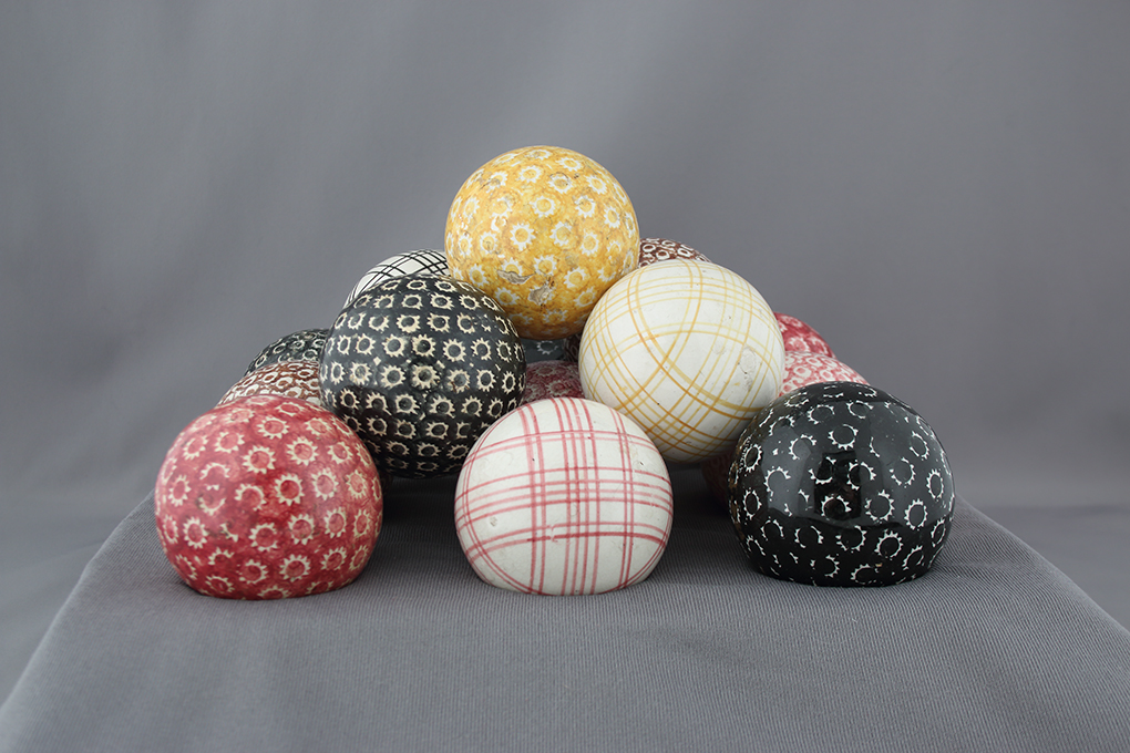 A collection of multicoloured carpet balls positioned in a pyramid.