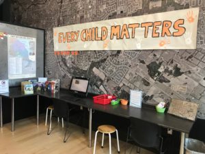 Families Gallery wall with a large banner. The banner is hand painted and reads Every Child Matters in orange and black paint.