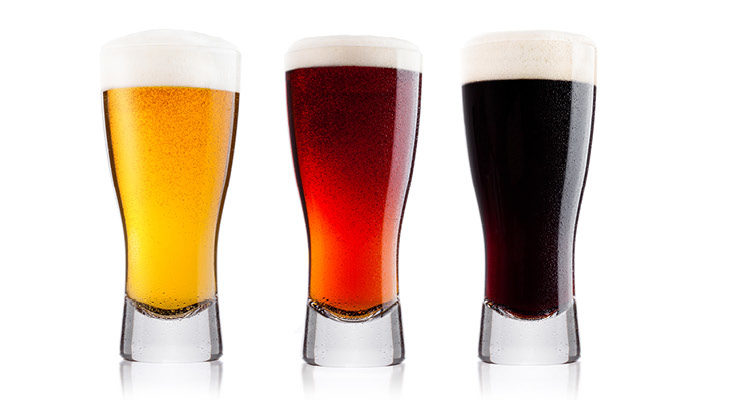 Three pints of beer, far left is a light pale ale pint, middle pint is amber in colour, far right pint is a dark stout.