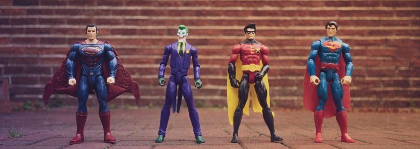 Stock image of four superhero action figures standing up against a brick wall.