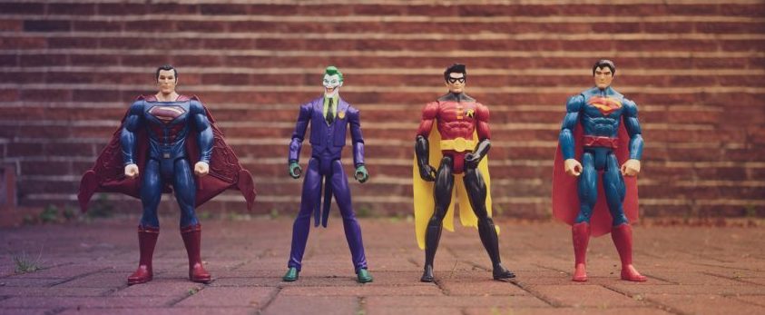 Stock image of four superhero action figures standing up against a brick wall.