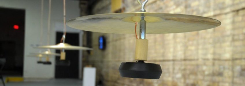 Gordon Monahan's piece called Cymbalism. Three altered cymbals are hung from the ceiling in a row.