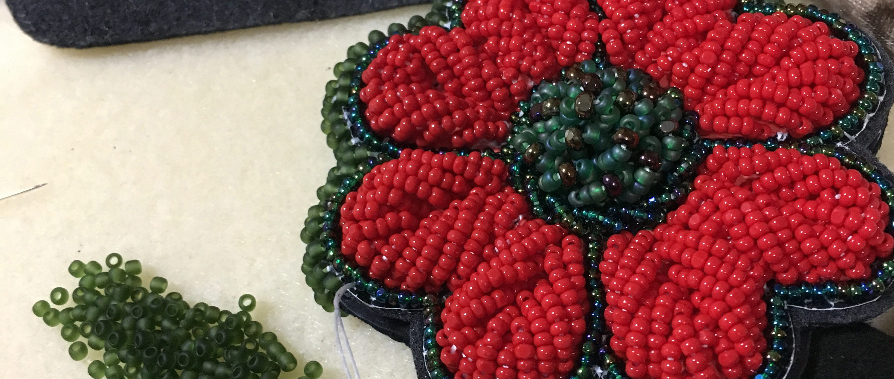 Red and green beaded poppy made by First Nations artist Naomi Smith.