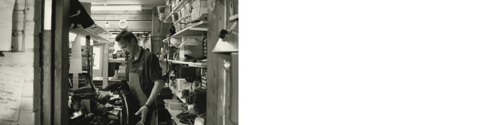 Photo of Diego Hadarits of Dimar Shoe Repair. He is standing at a his shoe repair station and is working on a pair of shoes. You can see the portrait of his face.