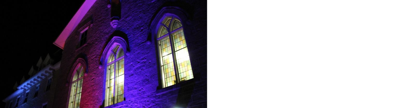 Photo of the exterior of the Civic Museum at night and lit up by purple and red lights.