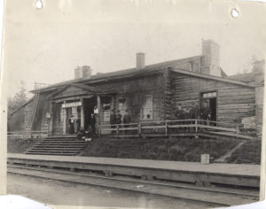 B&W. Glossy. The Priory, Guelph, when in use as the station for the C.P.R. Nine men and three women, none identified are standing or sitting in front of the building. One wearing a flat to cap may be the Station Master.