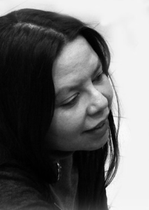 Profile photo of Naomi Smith in black and white. Her face is shown looking away at the camera. She has straight black hair.