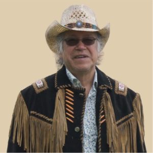 portrait photo of Rene Meshake. He is wearing a hat, glasses and beaded, fringed jacket.