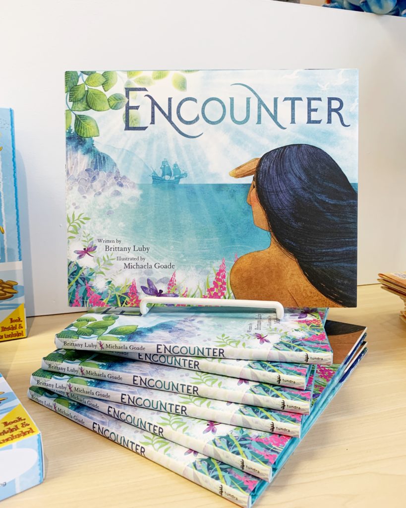 Encounter book. A stack of books is shown face-up on a shelf. The book cover has the title Encounter and a woman is looking off into the distance.