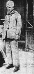 A black and white photo of man standing outside. He is wearing warm winter clothes and a hat. Little detail is shown in the photo since it is very old.