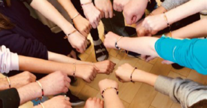 Children's hands gathered in a circle showing bracelets